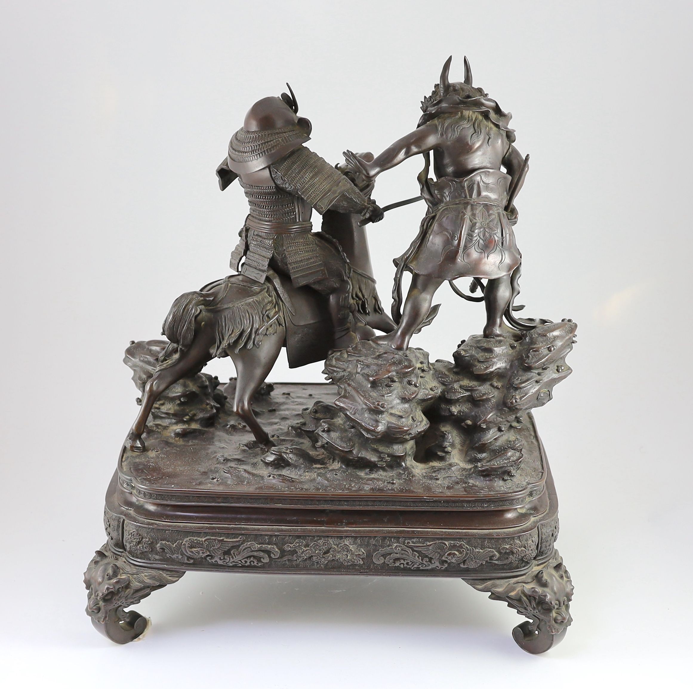 An impressive Japanese bronze group of an oni attacking a Samurai on horseback, Meiji period, 58cm high 49.5cm wide